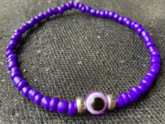 Purple evil eye protection anklet - custom size handmade seed bead evil eye anklet  Handmade purple evil eye protection anklet - made with love & infused with lots of positive vibes by me. Each purple evil eye anklet is made using 4 mm glass seed beads in a deep imperial purple shade combined with a purple evil eye charm & complimentary silver stainless steel beads. Stainless steel is hypoallergenic so the silver tone beads on your evil eye anklet will not tarnish. The beading thread I use for m Handmade Purple Anklets As Gift, Evil Eye Bracelet Purple, Purple Beaded Anklets, Bohemian Blue Evil Eye Bracelet Hand-strung, Adjustable Blue Hand-strung Evil Eye Bracelet, Summer Beach Jewelry, Beaded Anklets, Stretchy Bracelets, Evil Eye Charm