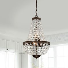 a chandelier hanging from the ceiling in a room with white walls and windows