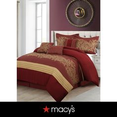 a red and gold comforter set with pillows on it in front of a purple wall