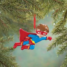 a christmas ornament hanging from a tree with a boy in a superman costume