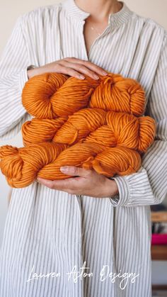 a woman holding orange yarn in her hands