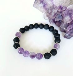 Amethyst and Lava Rock Bracelet, Essential Oil Diffuser Bracelet, Healing Gemstone Bracelet This high vibrational semi-precious gemstone bracelet is handmade with soothing lilac amethyst crystal and lava stone complimented with stainless steel spacers. 8mm Amethyst and black lava rock is strung on a strong stretch cord for a comfortable fit for your wrist. Boost your mood anytime around your wrist wearing Lava Rocks that are uniquely porous so they capture and carry oil releasing the scent like 8mm Amethyst Beaded Bracelets For Meditation, Amethyst Bead Bracelets For Healing, Amethyst Beaded Bracelets With 8mm Beads For Meditation, Amethyst 8mm Beads Bracelet For Meditation, Purple Bracelets With 8mm Beads For Healing, Amethyst Beaded Bracelets For Meditation, Spiritual Lava Stone Bracelets With 8mm Beads, Lava Stone Bracelets With Natural Stones For Gift, Gift Bracelets With Natural Lava Stones