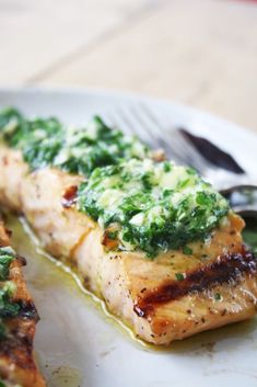 a white plate topped with meat covered in sauce and spinach on top of it