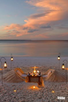 a table set up on the beach with candles