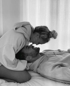 a man and woman laying in bed with one being kissed by the other's head