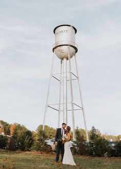 a bride and groom standing in front of a water tower