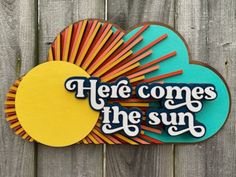 here comes the sun sign on a wooden fence