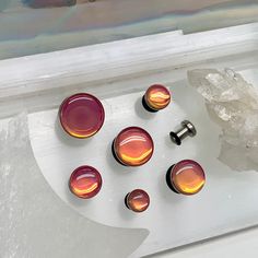 five glass knobs are sitting on top of a piece of white paper next to a rock