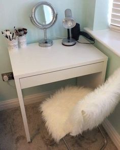 a white desk with a mirror, lamp and other items on it in a small room