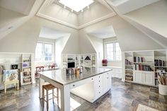 an open kitchen and dining room area with vaulted ceiling, white cabinets and stainless steel counter tops