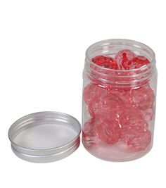 a glass jar filled with red gummy bears next to a metal container full of them