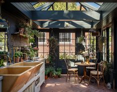 an outdoor kitchen with lots of potted plants on the table and chairs in it