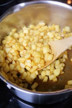 the food is being cooked in the pot on the stove top with a wooden spoon