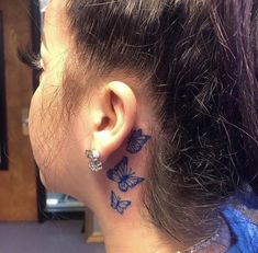 a woman's ear with blue butterflies on the back of her ear and behind her ear