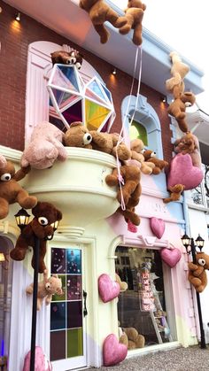 teddy bears hanging from the side of a building with hearts on it's windows