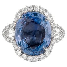 a blue and white diamond ring with an oval shaped center surrounded by smaller round diamonds