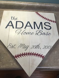 a wooden sign that says the adams's home base and is decorated with baseball stitches