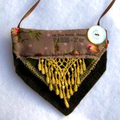 an ornament hanging from a string on top of a piece of cloth with a button