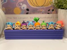 a group of small figurines sitting on top of a purple shelf next to a potted plant