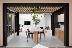 an office with pink walls and black framed windows, a white table surrounded by chairs