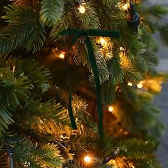 the christmas tree is decorated with green ribbon and small lights, which are hanging from it's branches