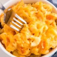 a white bowl filled with macaroni and cheese on top of a blue cloth