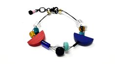 This fun and quirky bracelet is made of a mix of wood, glass, and semi precious stone beads and has an adjustable size. Most of my creations are inspired by the Memphis Milano art movement of the 80s and early 90s. Known for its colorful, bold, and playful designs, the style uses geometric shapes, clashing patterns, and unexpected combinations of materials. It embraces individuality, playfulness, and a sense of experimentation.  ◓ All pieces are handmade. Please handle with love and care◓ I can make custom pieces if feasible. Message me with your idea! ◓SHIPPING:◓ Domestic: Items will be shipped via USPS first-class. I ship in 3-7 business days of purchasing. Please allow an additional 3-7 days for delivery. We cannot be held responsible for shipping delays due to weather, holidays, etc. Quirky Bracelets, Clashing Patterns, Minimalist Art Deco, Modern Bracelet, Memphis Milano, Geometric Bracelet, Modern Bracelets, Bracelet Minimalist, Early 90s