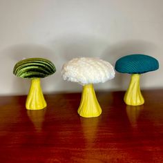 three different colored mushrooms sitting on top of a wooden table