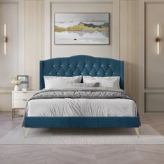 a blue bed with white sheets and pillows in a room that has beige walls, wood floors and wooden flooring