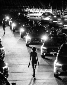 a black and white photo of people walking down the street at night with many cars