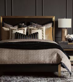 a bed with two pillows on top of it next to a night stand and lamp