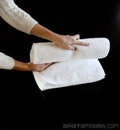 two hands holding white towels on top of each other in front of a black background