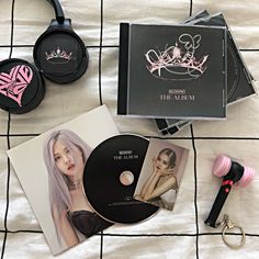 the contents of a makeup set including cd, ring, and keychain on a bed