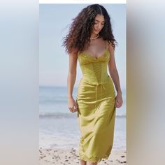 a woman in a yellow dress walking on the beach