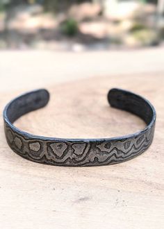 These bracelets are made to measures approximately 7 inches around and .5 inches in width. We are no longer taking custom orders for sizes at this time. Our damascus bracelets are hand forged from 1084 and 15n20. The damascus pattern varies with every bracelet; please expect that the one sent to you will be uniquely different in its own way. The photos show the general look of our hand-forged damascus. Each bracelet is coated with organic beeswax to protect it from the elements. As the wax coati Adjustable Hand-cast Bracelets As Gift, Hand Cast Adjustable Bangle For Gift, Adjustable Hand Cast Bangle As Gift, Adjustable Hand Cast Bangle For Gift, Adjustable Oxidized Cuff Bracelet, Artisan Etched Adjustable Bracelets, Adjustable Oxidized Finish Cuff Bracelet As Gift, Adjustable Hand Forged Cuff Bracelet, Unique Etched Adjustable Cuff Bracelet