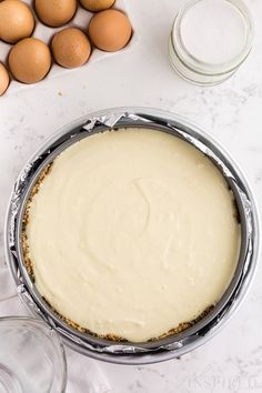 an uncooked pie sitting on top of a table next to eggs