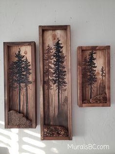 two wooden wall hangings with trees painted on the sides and rocks in between them