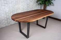 a wooden table sitting in front of a brick wall next to a potted plant