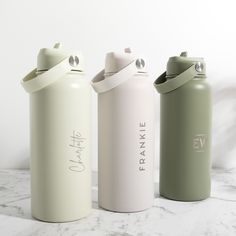 three different styles of water bottles on a marble countertop with white walls in the background