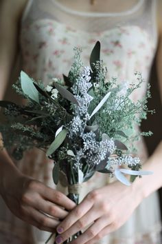 a woman holding a bouquet of flowers in her hands and wearing a ring on her finger