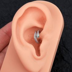 a person is holding an ear in their right hand and there are two diamonds on the inside of the ear