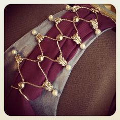 a close up of a horse's bridle with pearls and leaves on it