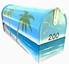 a mailbox painted with palm trees and the ocean on it's front cover