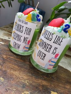 two glasses filled with green liquid sitting on top of a wooden table