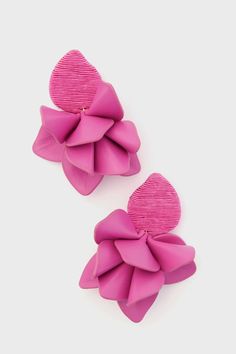 two large pink bows are attached to the back of a pair of ear clips,