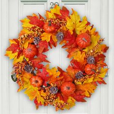 a wreath made out of autumn leaves and acorns is hanging on the front door