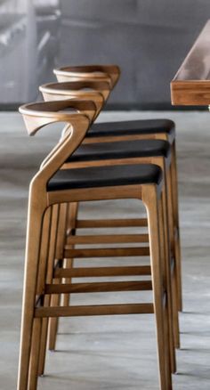 several wooden chairs sitting next to each other on top of a cement floor in front of a table