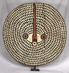 a wooden clock sitting on top of a white table next to a black and white wall