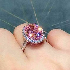 a woman's hand holding a pink diamond ring with diamonds on the band and inside