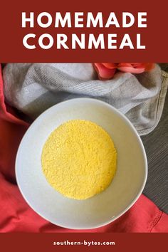 a white bowl filled with yellow cornmeal on top of a red cloth next to a